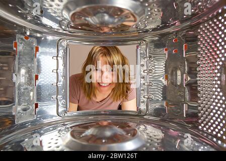Woman looking into washing machine at laundromat without clothing. Woman checking laundry from top load washing machine. Housework concept. Stock Photo