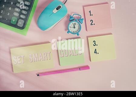 Handwriting text Set Smart Goals. Conceptual photo giving criteria to guide in the setting of objectives Notepads mouse alarm clock calculator sheet m Stock Photo