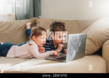 Kids studying at home using online lessons on laptop. Children watching online cartoons. Quarantine at home. Online education for kids. Stock Photo