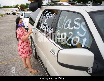 The sister of a graduate of Navarro Early College High School uses shoe polish to decorate a vehicle for a parade through their north Austin neighborhood to celebrate an academic finale shortened by the coronavirus pandemic. Stock Photo