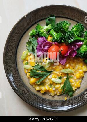 Indonesian cornmeal grits with broccoli, tomatoes, and sliced purple cabbage served on plate Stock Photo