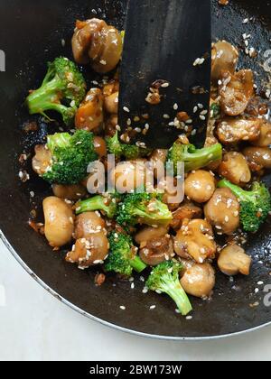 button mushrooms, broccoli, sesame seeds sauteed on a frying pan Stock Photo