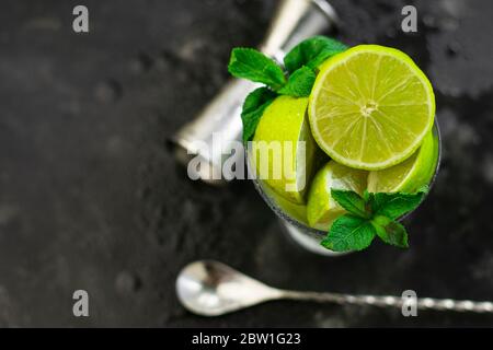 selective focus, sliced limes in a glass glass on a dark table with mint leaves Stock Photo