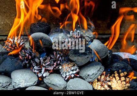 charcoal briquettes and pine cones burning in  a concrete barbecue fireplace Stock Photo