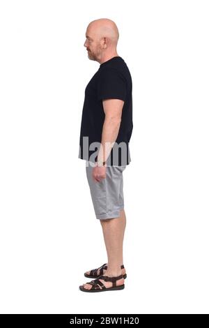bald man in profile with shirt shorts and sandals on white background Stock Photo