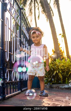 Margao, Goa/India - May 10 2020 : Playful Pretty Indian girl child/infant/toddler wearing a hair band, playing with a cycle/tricycle. Stock Photo