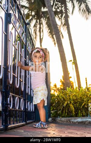 Margao, Goa/India - May 10 2020 : Playful Pretty Indian girl child/infant/toddler wearing a hair band, playing with a cycle/tricycle. Stock Photo