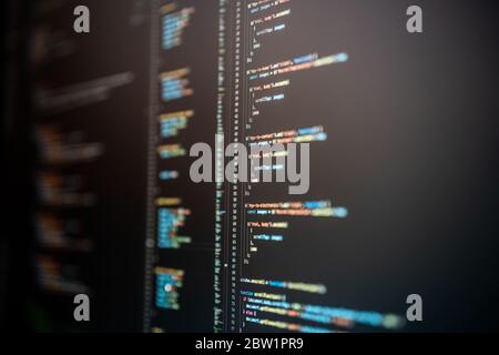 Javascript code in various colors on a dark mode computer screen. Stock Photo