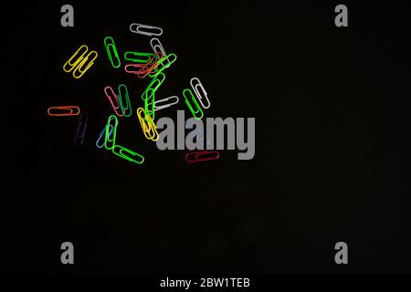 Fluorescent colored paper clips on black background Minimalist concept. Pair of dozens Stock Photo