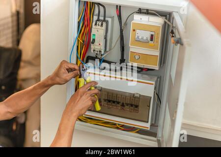 Electrician repairing electrical box with pliers at home. Stock Photo