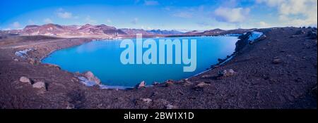 Panorama shot of a water filled volcanic crater in mountain landscapes on a sunny day Stock Photo