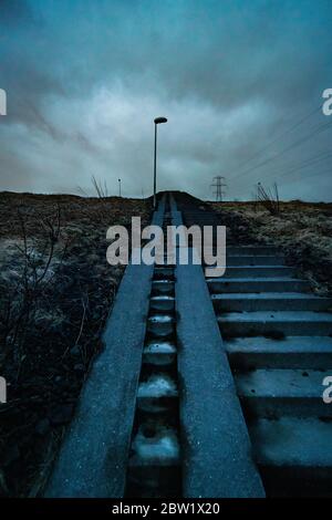 Low angle of an old staircase in a rural Icelandic area, leading up towards the grey skies Stock Photo