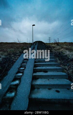 Low angle of an old staircase in a rural Icelandic area, leading up towards the grey skies Stock Photo