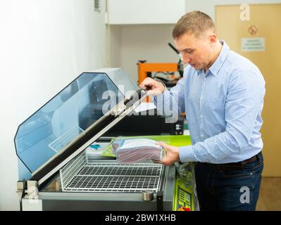 Worker using vacuum packing machine in printing shop Stock Photo