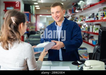Positive administrator of the printing house gives finished product to the buyer Stock Photo