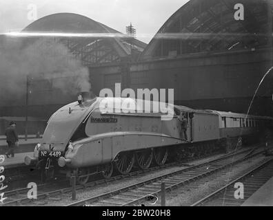 With a schedule under 4 hours for the 210 miles journey, the London and North Eastern Railway's new Coronation streamlined train speeding north to Grantham on a trial run. The locomotive drawing the express is Dominion of Canada, one of the fastest in the British Empire. The train at King's Cross station. 30 June 1937 Stock Photo