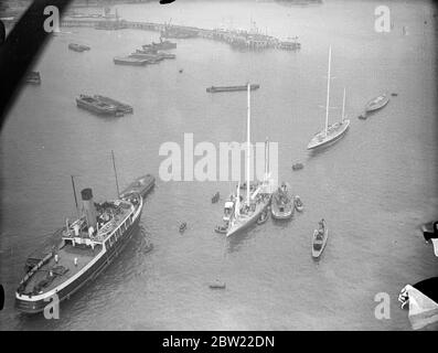 A view from the air as other craft flocked around the yacht to welcome her on her arrival. Captain Nad Heard, master of the endeavour I, after bringing their yachts safely into port in Hampshire. After their lone 2000 mile voyage across the Atlantic. 1 October 1937. Stock Photo