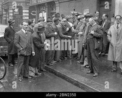 Thousands of idle in East End, Master Tailor Strike. 'Manufacturers', or master tailors, dealing in women's coats and skirts, and declared a strike in East End London. They are demanding, among other things, an immediate increase of 20% of present prices from the wholesalers, with a minimum standard of 4s per garment. According to Mr A Blondin, secretary of the Masters organisation, 700 factories are closed on thousands of workers idle. Photo shows, workers made idle by the strike, discussing the situation outside the East End factory. 20. September 1937 Stock Photo