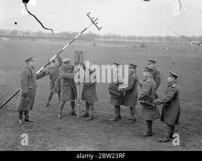 Army shows how 'communications are keeping pace with mechanisation'. Demonstrating that the vital part of 'communications'is keeping pace with the mechanisation of the army, the Royal Corps of signals , gave a display on their latest apparatus at Aldershot, Hampshire. Inter communication apparatus, radio, telephon and radio and telegraphy with mechanised cable layers were included in the demonstration. Photo shows, officers watching the Army Communication Corps men putting out radio masts for the 'for why you air line' system of communications at Aldershot. 15 February 1938 Stock Photo