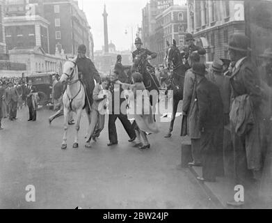 Following peace demonstrations in Trafalgar Square, riots broke out in Whitehall and The Mall when members of the crowd tried to break through police cordon to Downing Street. Mounted and feet police charged the crowds repeatedly. Photo shows: A policeman struggling with an arrested rioter in Whitehall as a girl attempt rescue. Two mounted officers are joining in, and the one on the left has the struggling man by the collar. 18 September 1938 Stock Photo