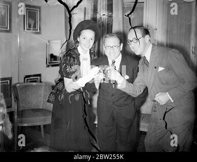 Jessie Matthews toasts Louis Levy's new BBC venture. To celebrate the commencement of Louis Levy's contract with the BBC for his Augmented Variety Orchestra of 30 musicians, a cocktail party was given at the Savoy Hotel, Strand. Leading figures in the entertainment world were present. The Orchestra will appear in 'You Shall have Music', which has been booked for twelve weekly broadcasts. Photo shows, Jessie Matthews and her husband, Sonnie Hale, toasting Louis Levy at the cocktail party. Miss Matthews is singing in the first programme. 5 July 1938 Stock Photo