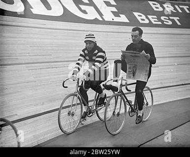 Reading a wheel in six days cycle race at Wembley. The second six-day cycle race is in progress at the Empire, Pool, Wembley, having started a few minutes after midnight. Photo shows, Piet Van Kempen (Holland) reading a newspaper as he cycles round the track. Alongside is Michel Pecqueux (France) in striped jersey. 2 May 1938 Stock Photo