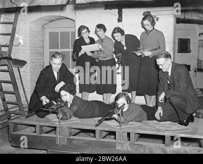 London office girls become expert with the rifle. Girls employed in the offices of the Crown Agents for the Colonies at Millbank, London, have a new interest. They have invaded the shooting range constructed in the basement of the building and spend their lunch hour and much of the time after hours practising marksmanship. They have entered for competitions. Photo shows, two of the girls being instructed by men at the range. 28 January 1938 Stock Photo