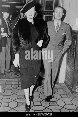 Marlene's 'Turban' fashion, at Hollywood Premiere. Marlene Dietrich, the film actress, wearing a turban style hat fashion and furs when she arrived with Andy Lowler for the premiere of the 'Goldwyn Follie' at the Hollywood Theatre in Los Angeles. 6 February 1938 Stock Photo