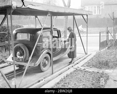 'Pushbutton' garage beneath the front garden. London man solves car owners problem. The main problem confronting the owners driver, that of garageing his car, conveniently and at least expense has been solved by a London man, Mr R B Bourdillon of Frognal Lane, in the suburb of Hampstead. When he arrives home, Mr Bourdillon drives onto an innocent looking concrete slab in his garden, goes into his house, presses a button and the card descends into its garage, a watertight concrete pit sunk in the earth. The roof of the garage forms part of the front garden. When the car is needed again, a touch Stock Photo