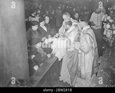 Italians kiss the Bambino at annual ceremony. Children of the Italian colony, tucked away in the little streets behind Clerkenwell Road, attended the annual ceremony of 'Kissing the Bambino'in the Italian church, Clerkenwell. The Bambino, a doll representing the Holy Child, was held by priest and the children are kissed it at the altar. Photo shows, a child kissing the Bambino at the ceremony. 16 January 1938 Stock Photo