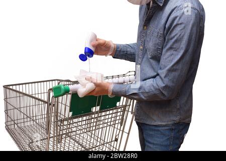 Supermarket consumer cleaning the shopping cart with disinfectant hydroalcoholic gel before buying protected with gloves and mask close up Stock Photo
