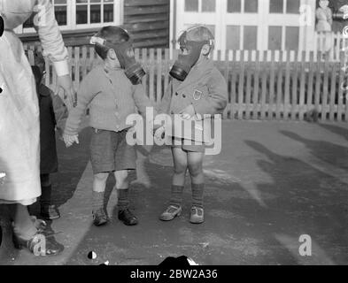 Gas mask tests for babies a Kent nursery. Babies only a few months old, were fitted with gas masks when Home Office experts conducted test at Dr Barnardo's Baby is Castle at Hawkhurst, Kent. The government has already and order of millions of masks for the adult population, but so far no efficient device for babies has been produced. The trials were made to discover the earliest age a child might be able to use a respirator and weeder extras for masks would be needed. Photo shows, two children in respirators during the test at the nursery. 20 October 1937 Stock Photo