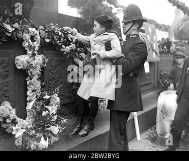 Trafalgar Day 1916. A kindly policeman lifts a little girl that she may deposit a wreath in memory of a near relative lost in a submarine. 21st October 1916 Stock Photo