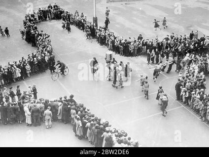 Under the instructions of policemen, schoolchildren of Stockholm, Sweden, are given lessons in safety first. Streets are chalked in the school playground, miniature traffic lights installed and the children simulate cars and trams in the lessons. Photo shows: The traffic lesson in progress in the playground of a Stockholm school under the direction of a policeman. 16 October 1938 Stock Photo