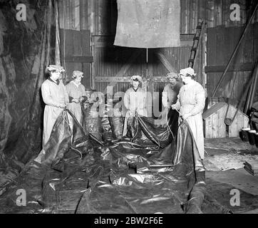 Women as tarpaulin makers. One of the latest tasks to be taken over by women war workers is the making and repairing of tarpaulin sheets. The sheets are mostly used by the war office forage dept. for covering forage, splicing on ropes to sheets. 20 April 1918 Stock Photo