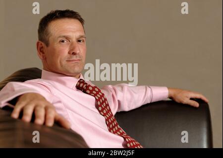 A businessman sitting confidently on a brown leather sofa Stock Photo