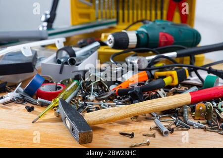 Various fasteners, supplies and hand tools in mess on wooden table. DIY home improvement concept Stock Photo