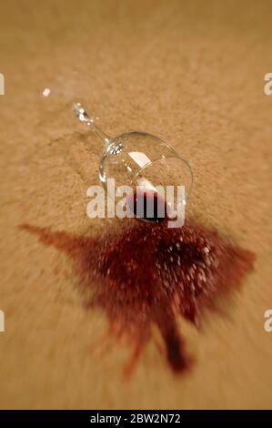 A glass of red wine spilling on a carpet Stock Photo