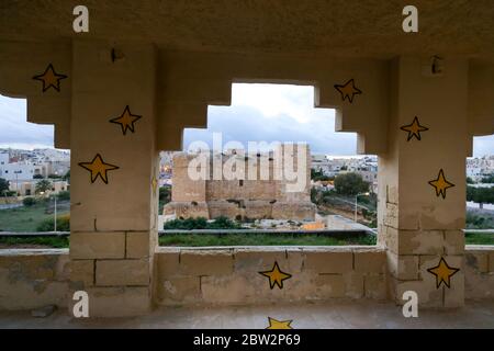 View of the St. Thomas Tower through the arc of a building in Marsaskala, Malta Stock Photo