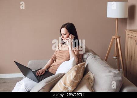 Unemployed woman talking on cellphone and browsing work opportunities online on laptop Stock Photo