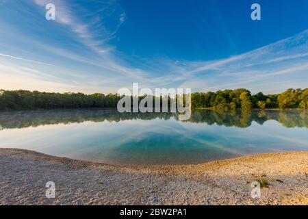 Small local recreation swimming lake in Bavaria, Germany in early morning light with fog over water Stock Photo