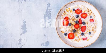 Healthy breakfast, bowl with oat granola, milk and berries, top view. Stock Photo