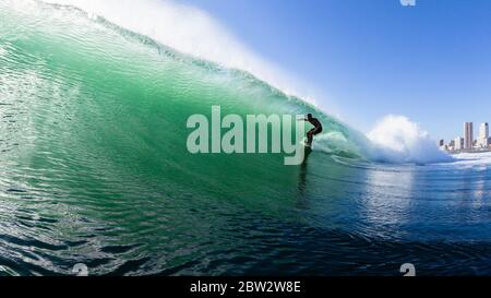 Surfer silhouetted rides hollow ocean wave summer tropical water swimming photo closeup action panoramic landscape Stock Photo