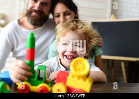 Parents watching son play with colorful bricks, defocused Stock Photo