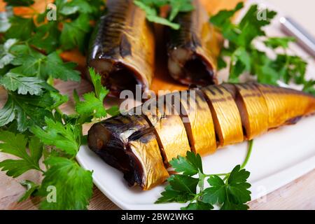 Smoked mackerel cut into pieces with parsley on a table Stock Photo