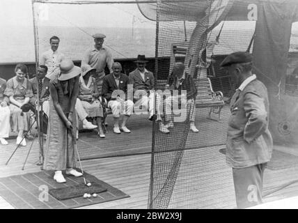 Deck games on board an ocean liner in the 1930s. Here a female passenger is taking part in a golf contest. She is aiming to hit the ball at a target painted on the back netting (right). Stock Photo