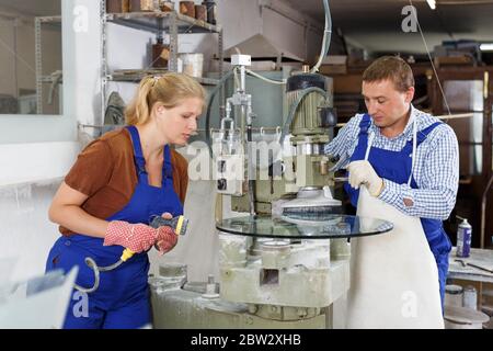 Serious craftsman working on machine for processing of curved facet of glass in workshop Stock Photo