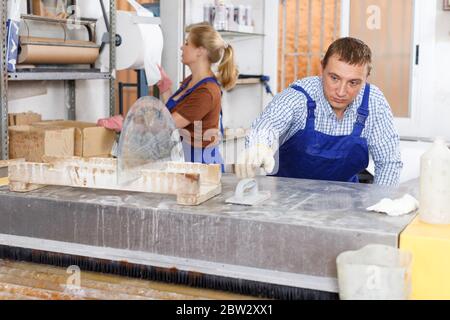 Focused male worker with female apprentice working on glass washing machine in workshop Stock Photo