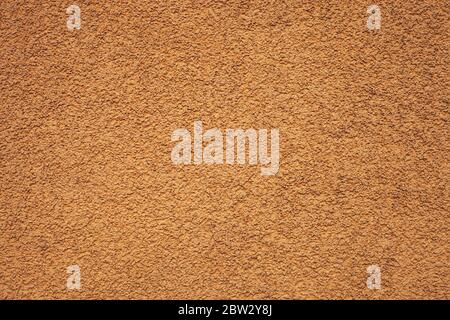 Texture orange pebble dash stucco facade. House wall brown grainy finishing plaster exterior pattern. Abstract rough background vivid color Stock Photo