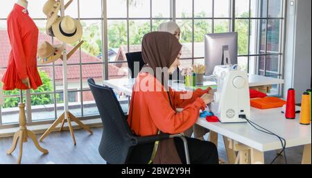 Small business of Muslim woman fashion designer Working and  using smart phone and tablet With Dresses at clothing store Stock Photo